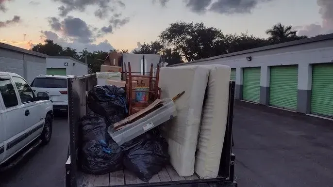 a man is carrying a bag of trash next to a garbage truck .