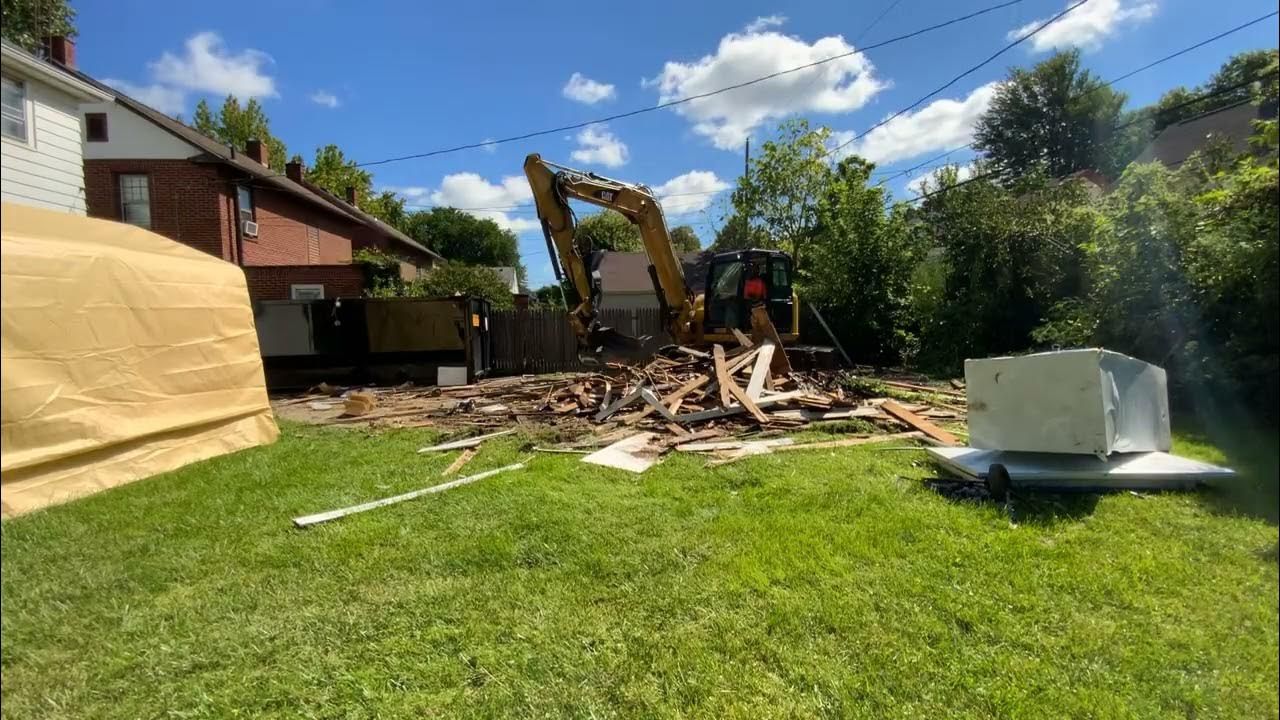 a man is carrying a bag of trash next to a garbage truck .