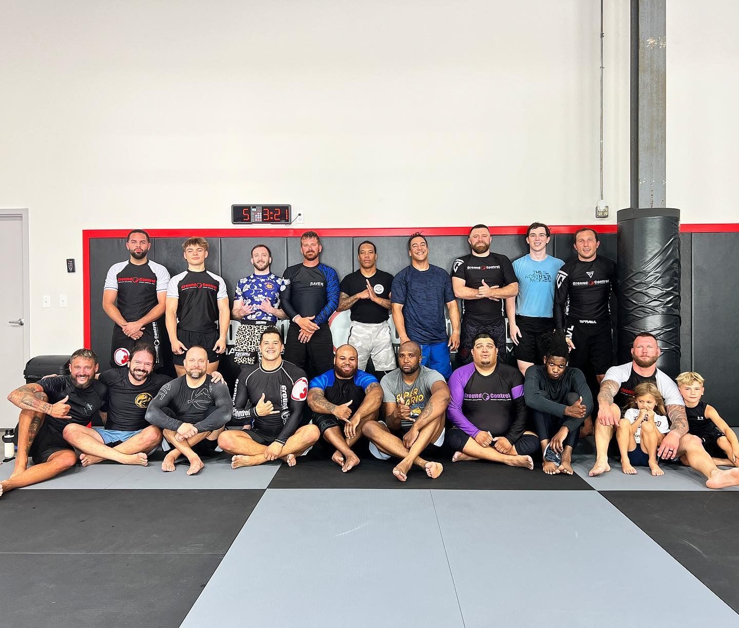 Group of people in workout attire posing together inside a gym with black and red accents.