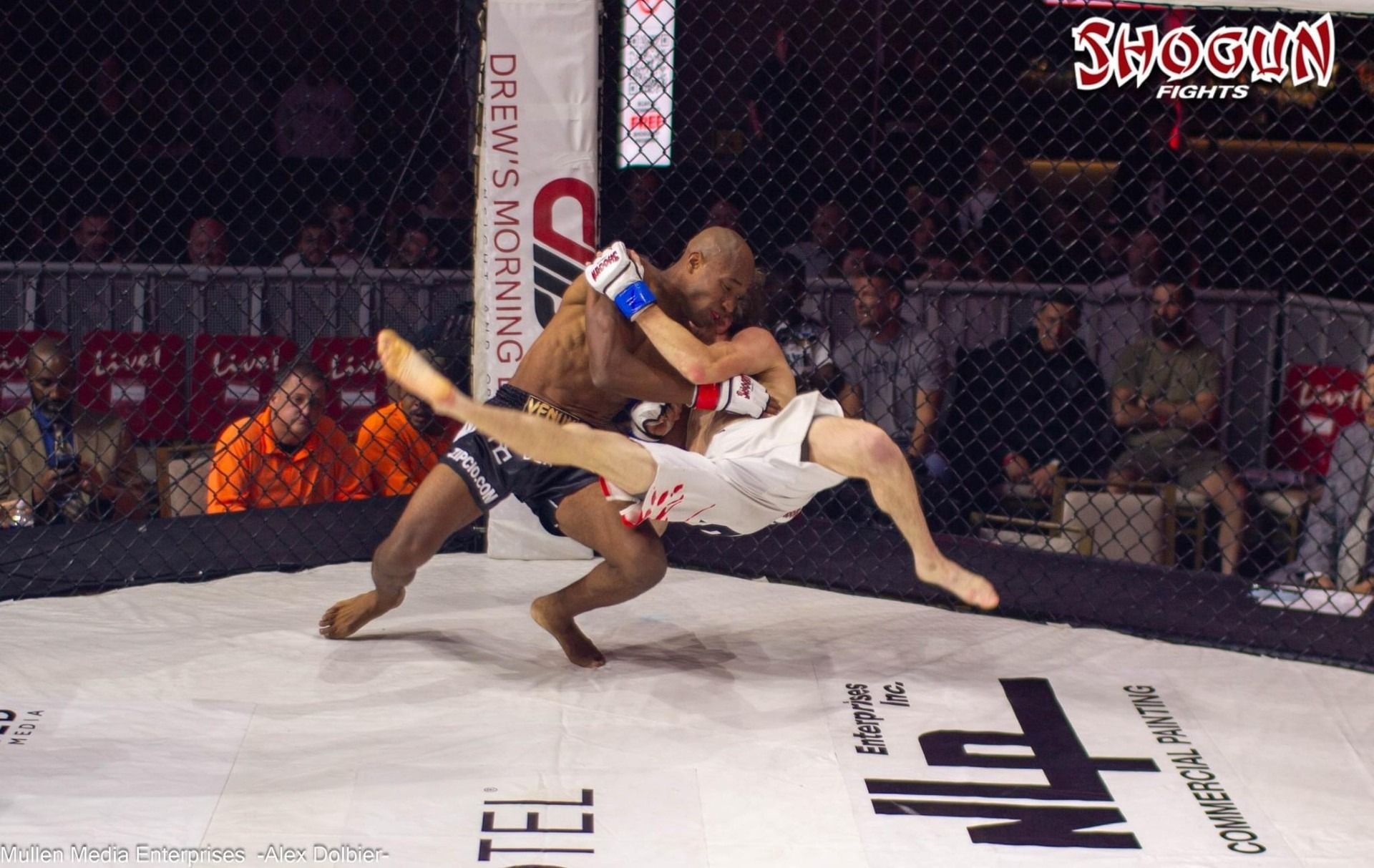 MMA fighter executing a takedown in a ring; one fighter lifts opponent, legs in air.