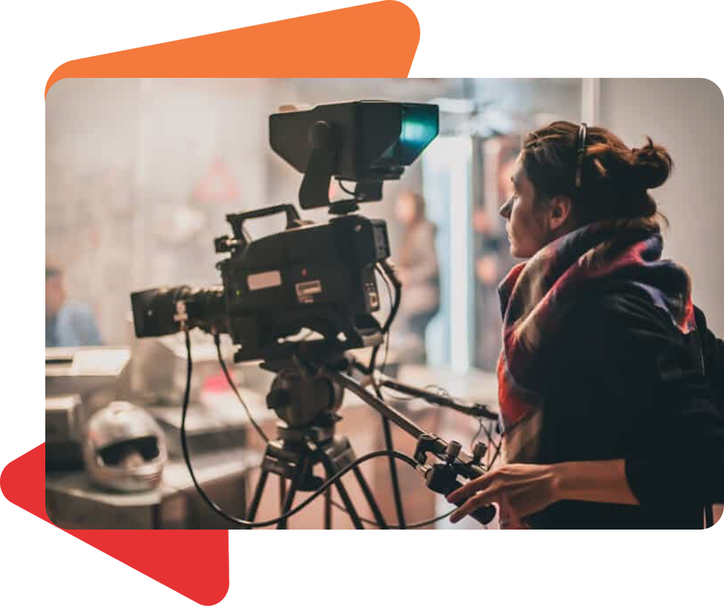 A person wearing a scarf operates a professional video camera on a tripod in a studio setting.