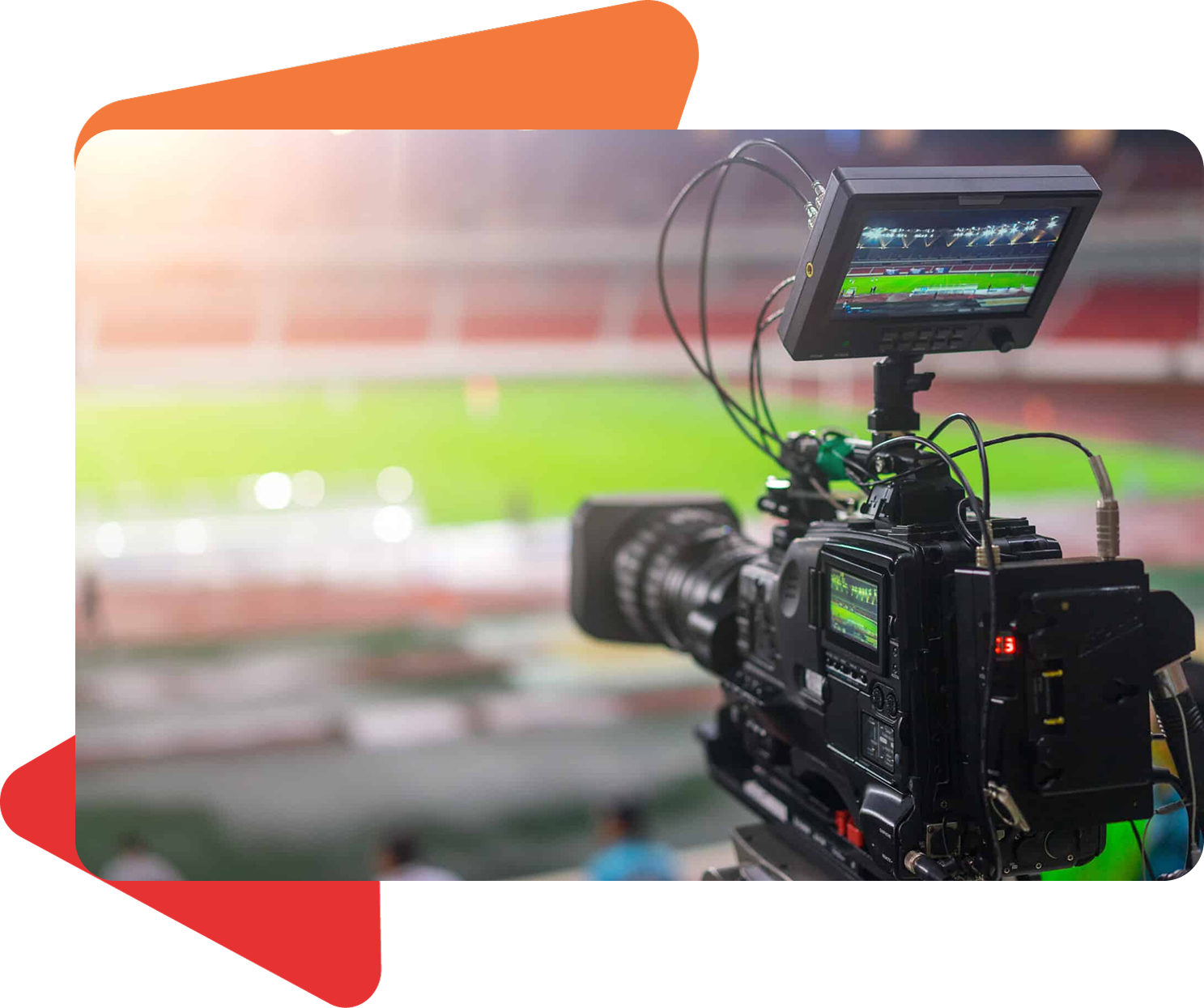 A professional video camera records a stadium field at night, focusing on a monitor displaying the live broadcast.