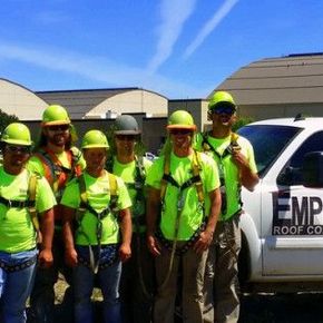 A group of construction workers are posing for a picture in front of a truck that says emp roof co.