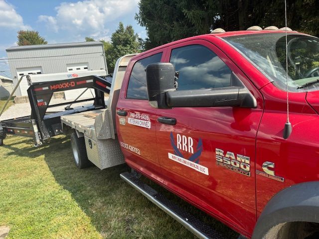 A red tow truck is parked in a grassy field.