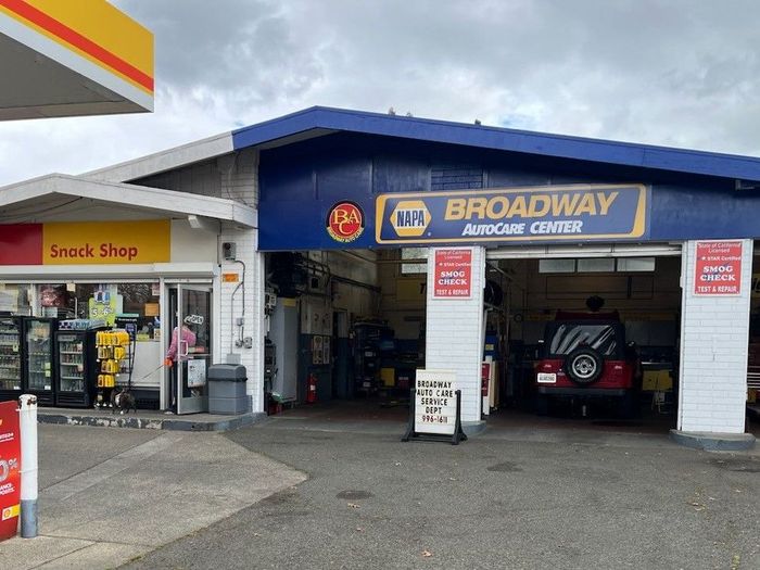 A car is parked in front of a broadway auto repair shop.