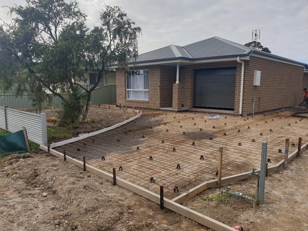 A Brick House Is Being Built With A Concrete Driveway In Front Of It — Turn It Crete in St Georges Basin, NSW