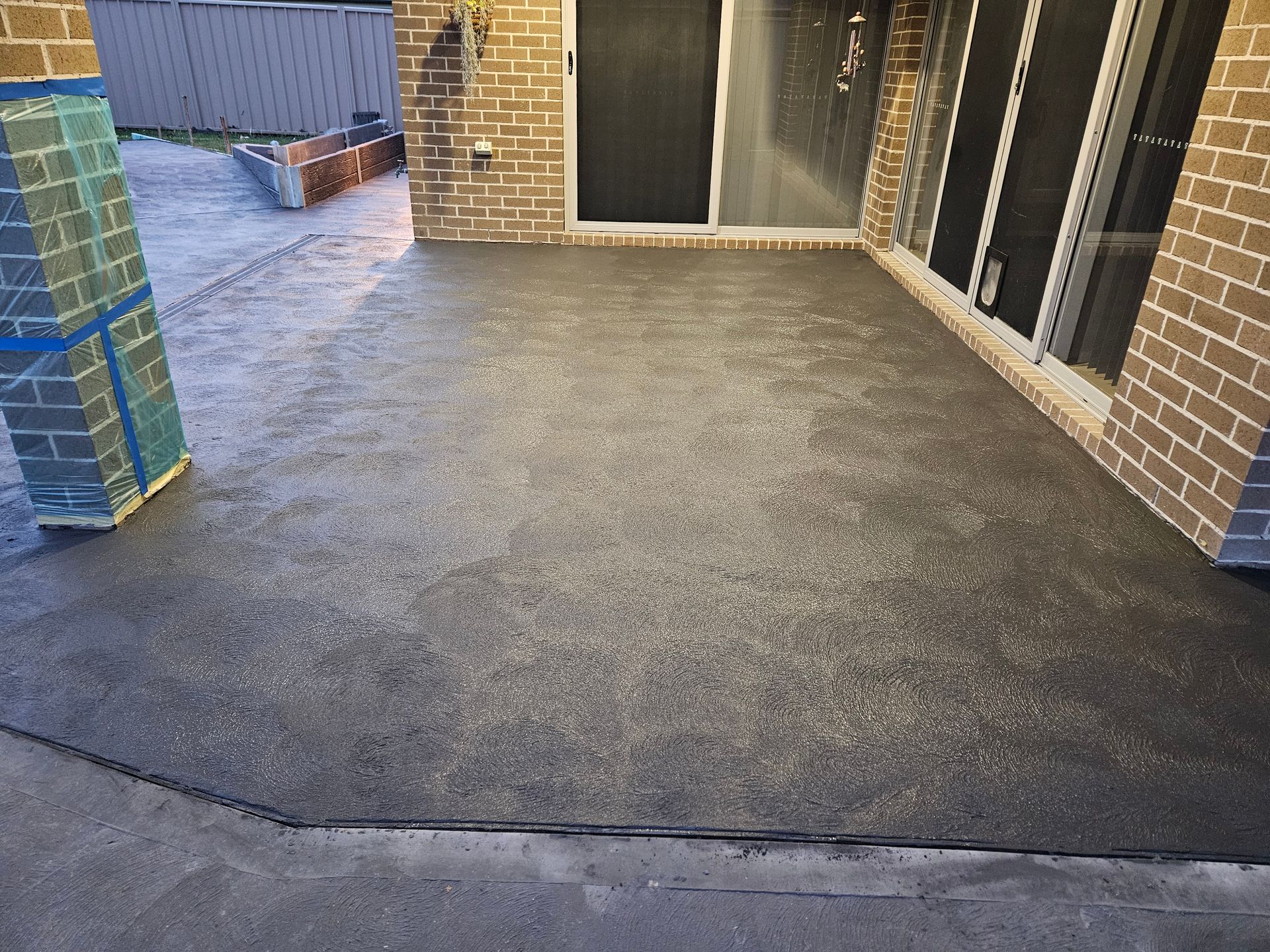 A Black Tiled Patio With White Lines Leading To A Garden — Turn It Crete in St Georges Basin, NSW