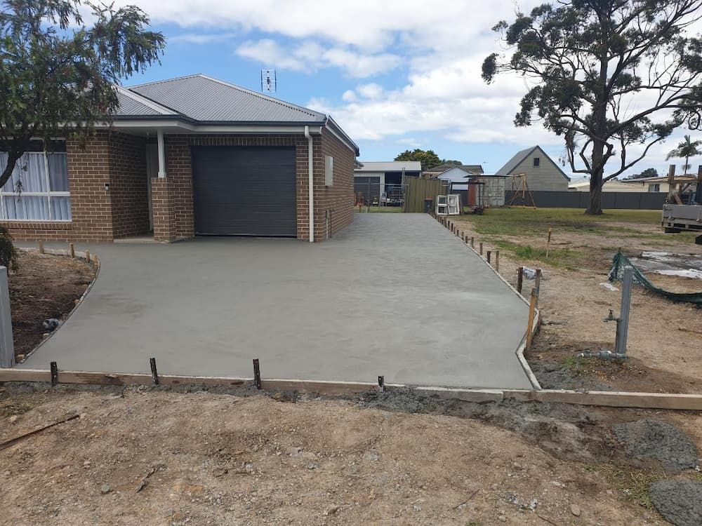 A Brick House With A Concrete Driveway In Front Of It — Turn It Crete in St Georges Basin, NSW