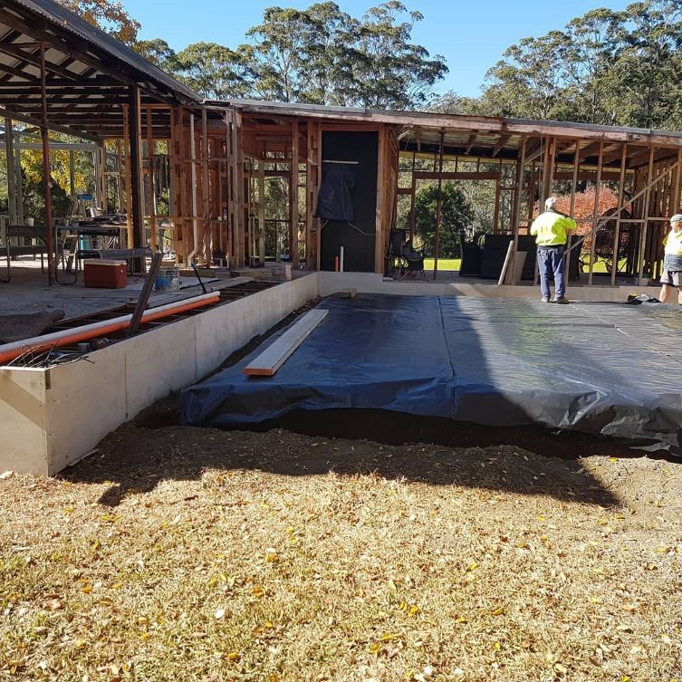 A Man in A Yellow Shirt Is Standing in Front of A Building Under Construction — Turn It Crete in Vincentia, NSW