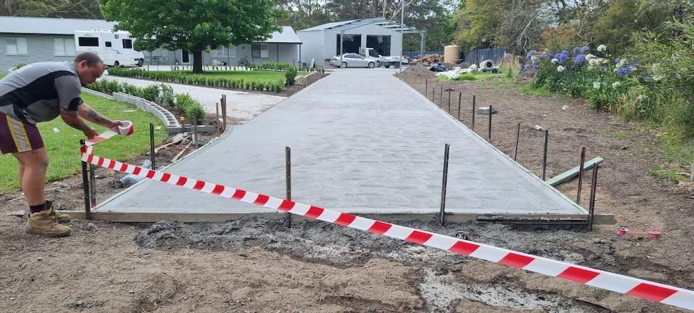 A Man Is Measuring A Concrete Driveway With A Tape Measure — Turn It Crete in St Georges Basin, NSW