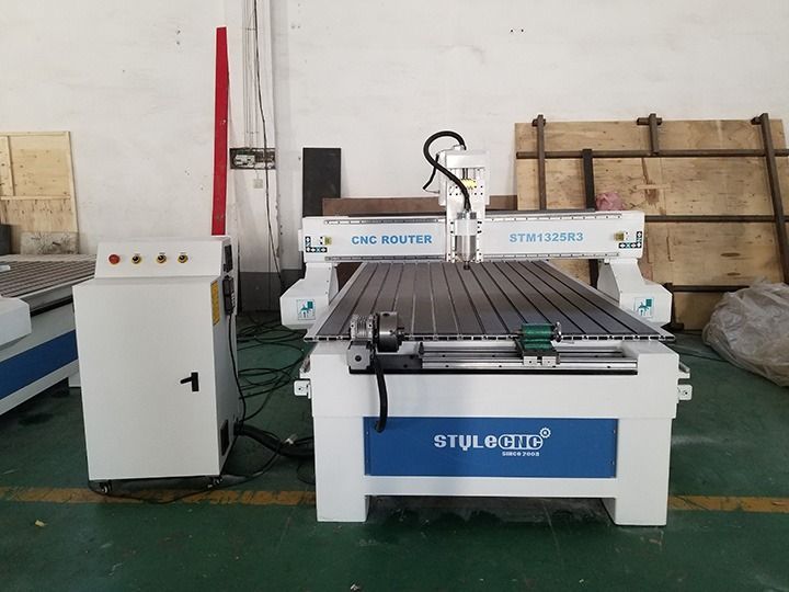 CNC router machine with white and blue frame, control panel, and work table in a workshop.