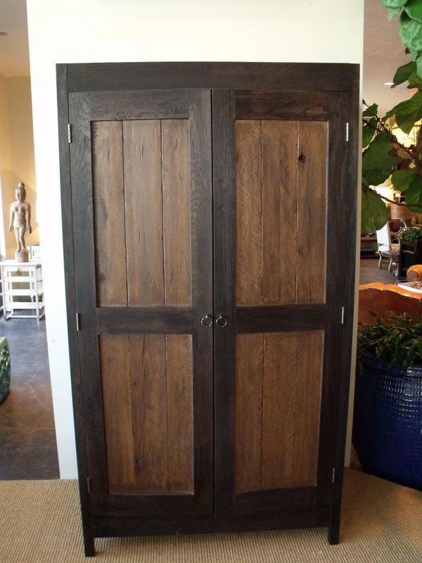 A wooden cabinet is sitting in a room next to a potted plant.