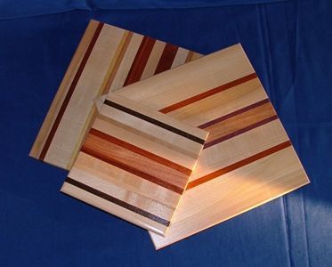 Three wooden cutting boards are stacked on top of each other on a blue surface