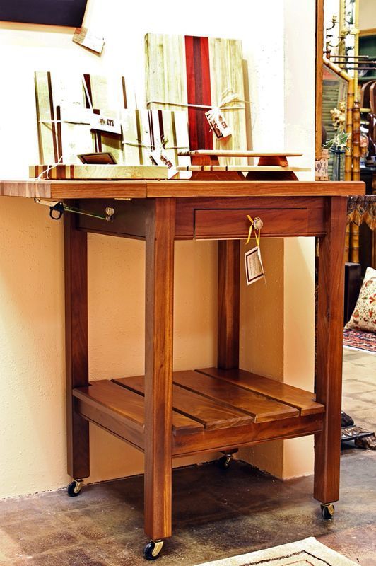 A small wooden table with wheels and a drawer