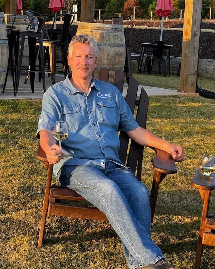 A man is sitting in a chair holding a glass of wine.