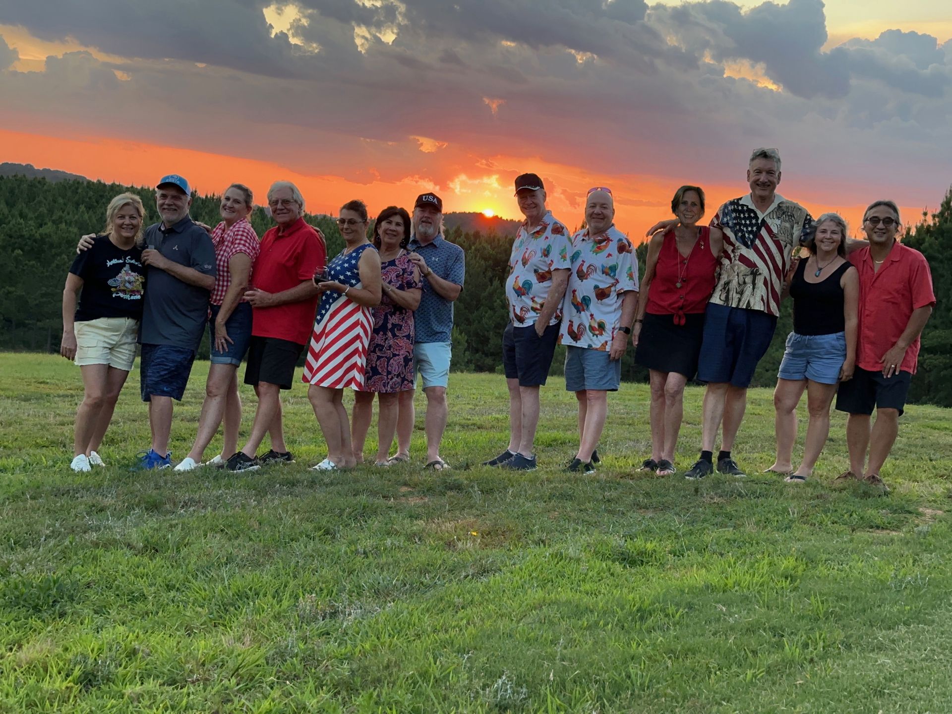 A group of people are posing for a picture in a field at sunset.
