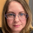 A close up of a woman wearing glasses and a black shirt