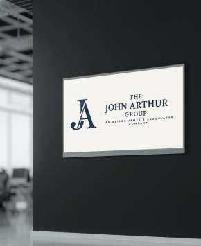 Sign for The John Arthur Group on a dark wall.
