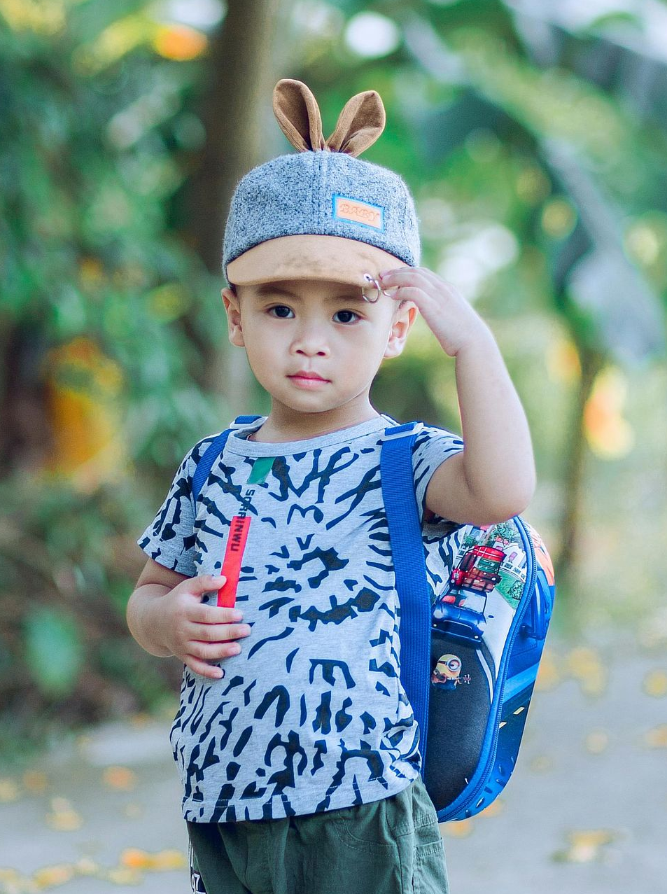 Boy in hat with bunny ears, backpack, and patterned shirt at Play's Kool Floreat.