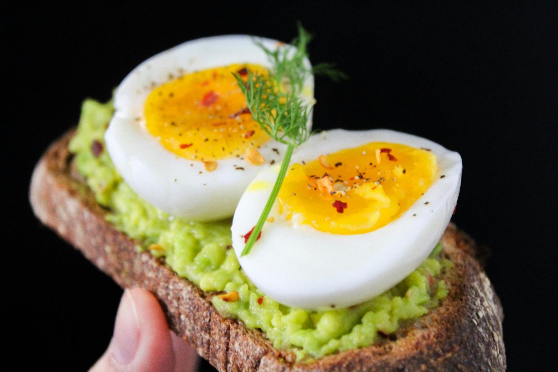 Avocado toast topped with sliced soft-boiled egg, garnished with herbs. Healthy Meal at Play's Kool Floreat Childcare Centre.