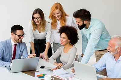 A group of people are sitting around a table looking at laptops.