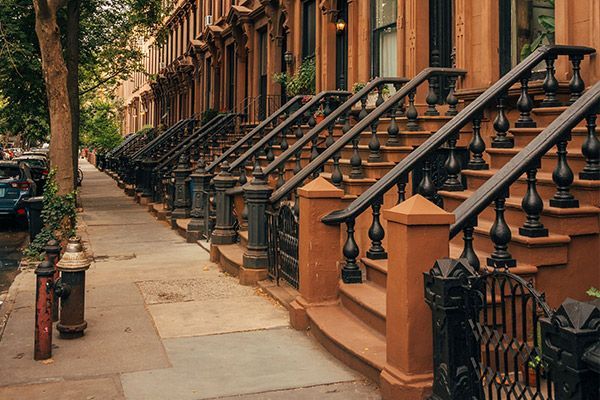 A row of houses with stairs leading up to them on a city street.