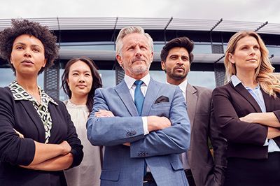 A group of business people standing next to each other with their arms crossed in front of a building.