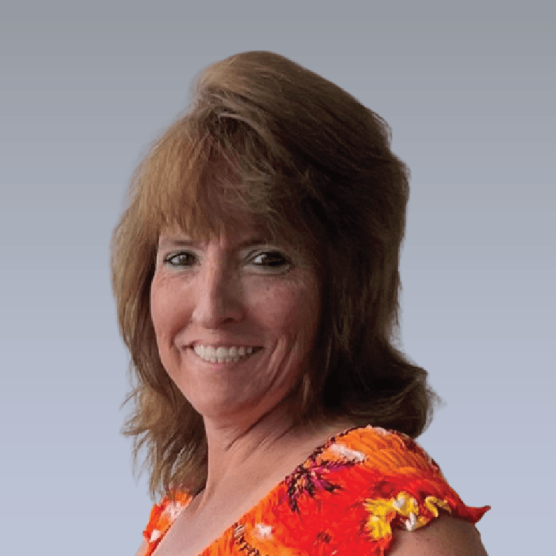 A woman wearing a red floral top smiles for the camera