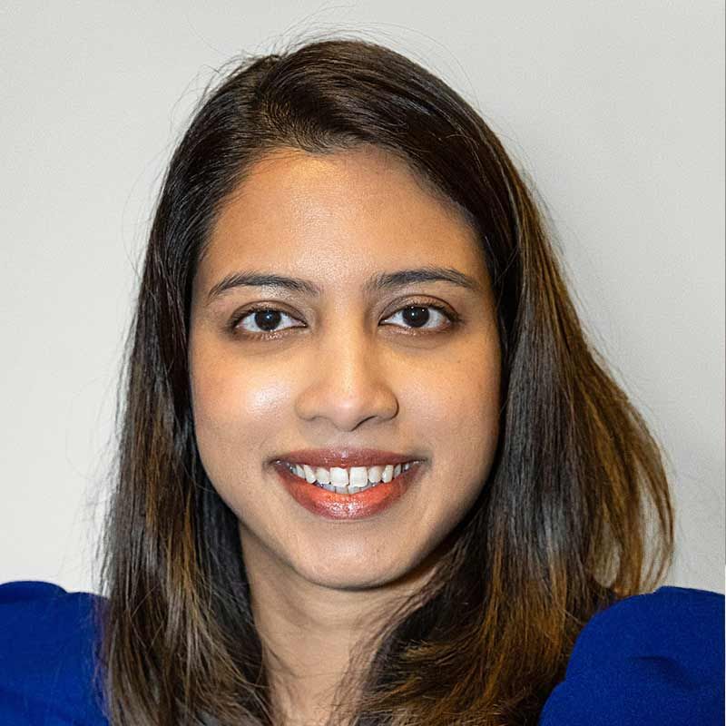 A woman in a blue shirt is smiling for the camera.