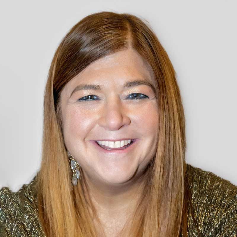 A woman with long brown hair is smiling for the camera.