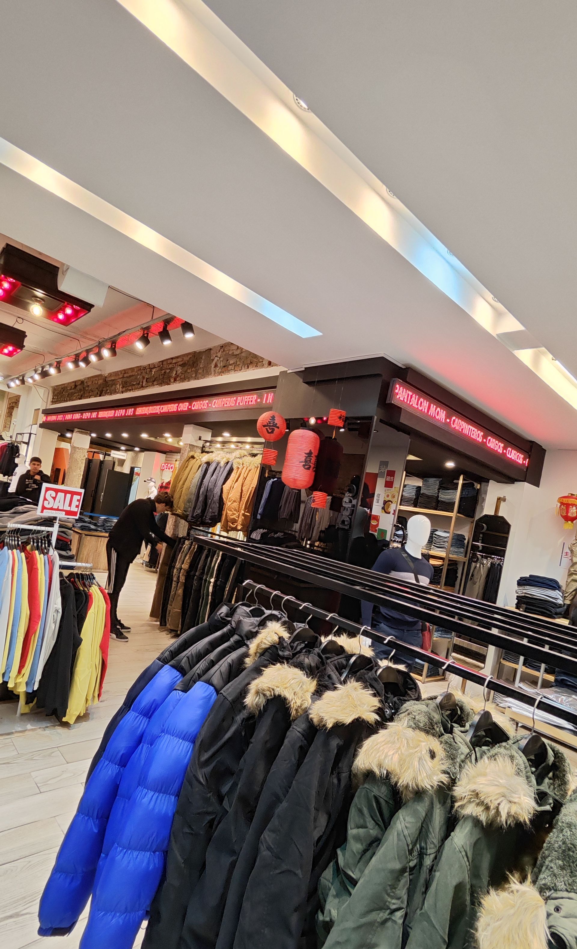 Interior de una tienda de ropa con percheros repletos de chaquetas y abrigos.