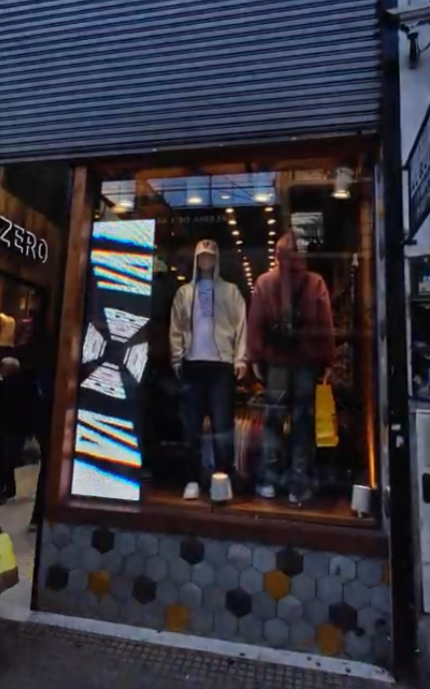 Escaparate con maniquíes vestidos con sudaderas con capucha y vaqueros. 