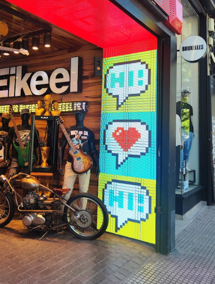 Entrada de una tienda de ropa con maniquíes, motocicleta y bocadillos de diálogo pixelados.