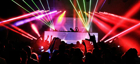 Concierto con público, DJ en el escenario y luces láser de colores.