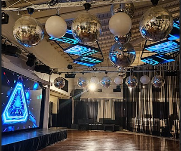 Interior de discoteca con bolas de discoteca y un escenario con iluminación azul.