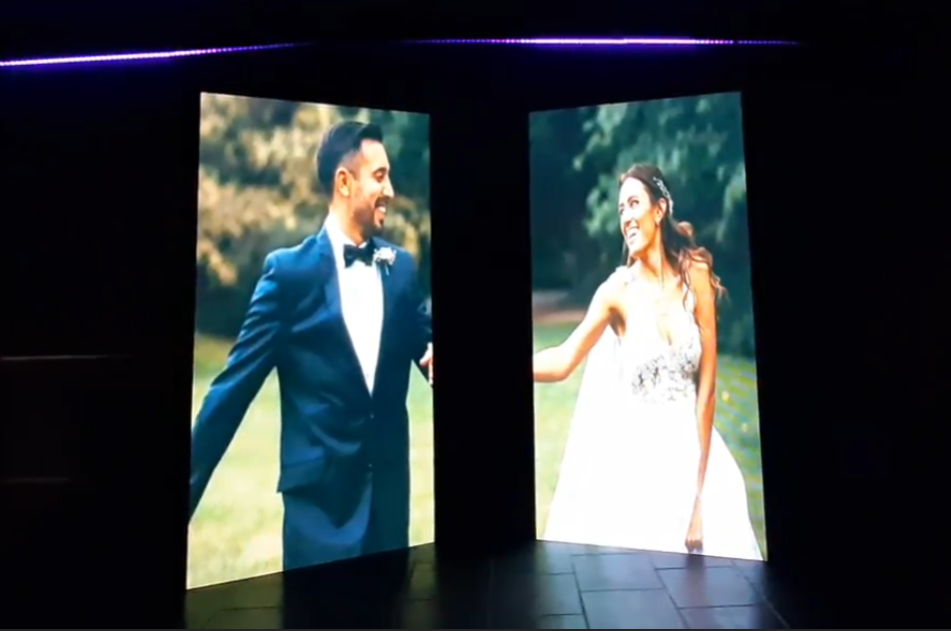 Pareja de recién casados ​​sonriendo en pantallas, vestidos de gala, al aire libre.