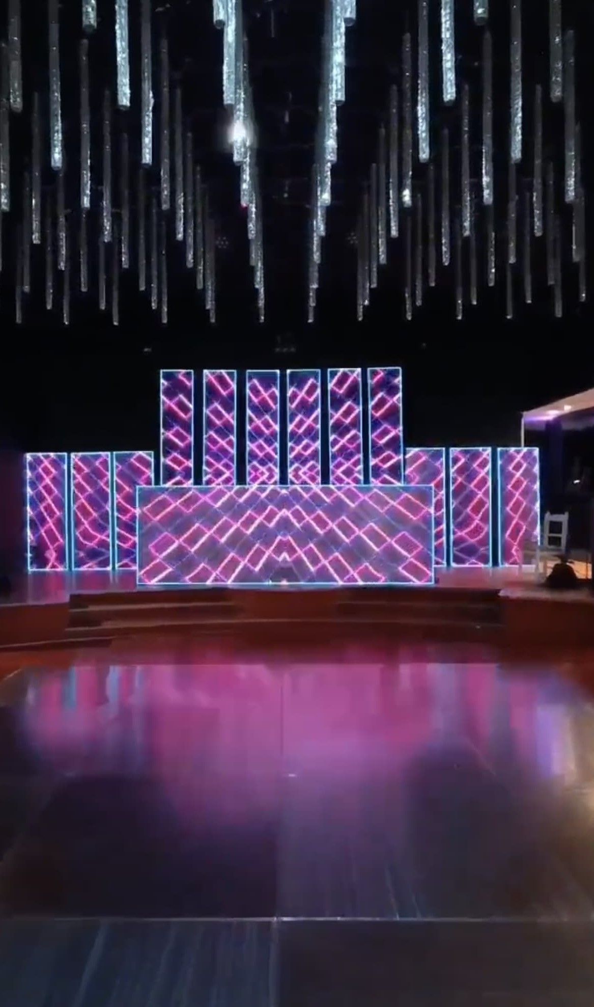 Escenario con paneles LED de color rosa brillante y azul, bajo un techo decorativo.