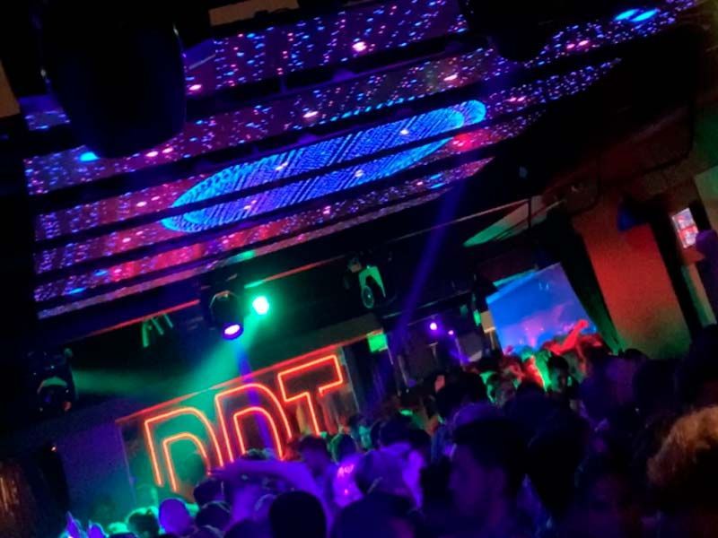 Gente bailando en una discoteca iluminada con luces de neón. 