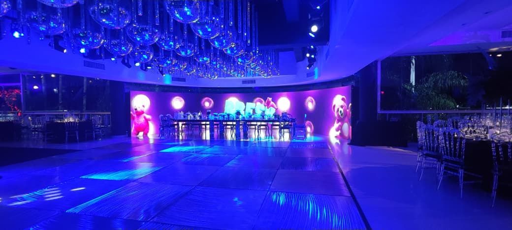 Una pista de baile en un local iluminado con luces azules y bolas de discoteca colgando del techo.