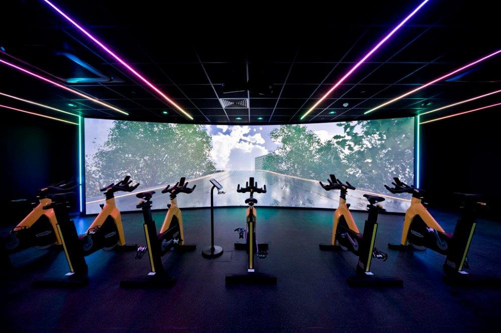 Estudio para clases de spinning con bicicletas estáticas frente a una gran pantalla 