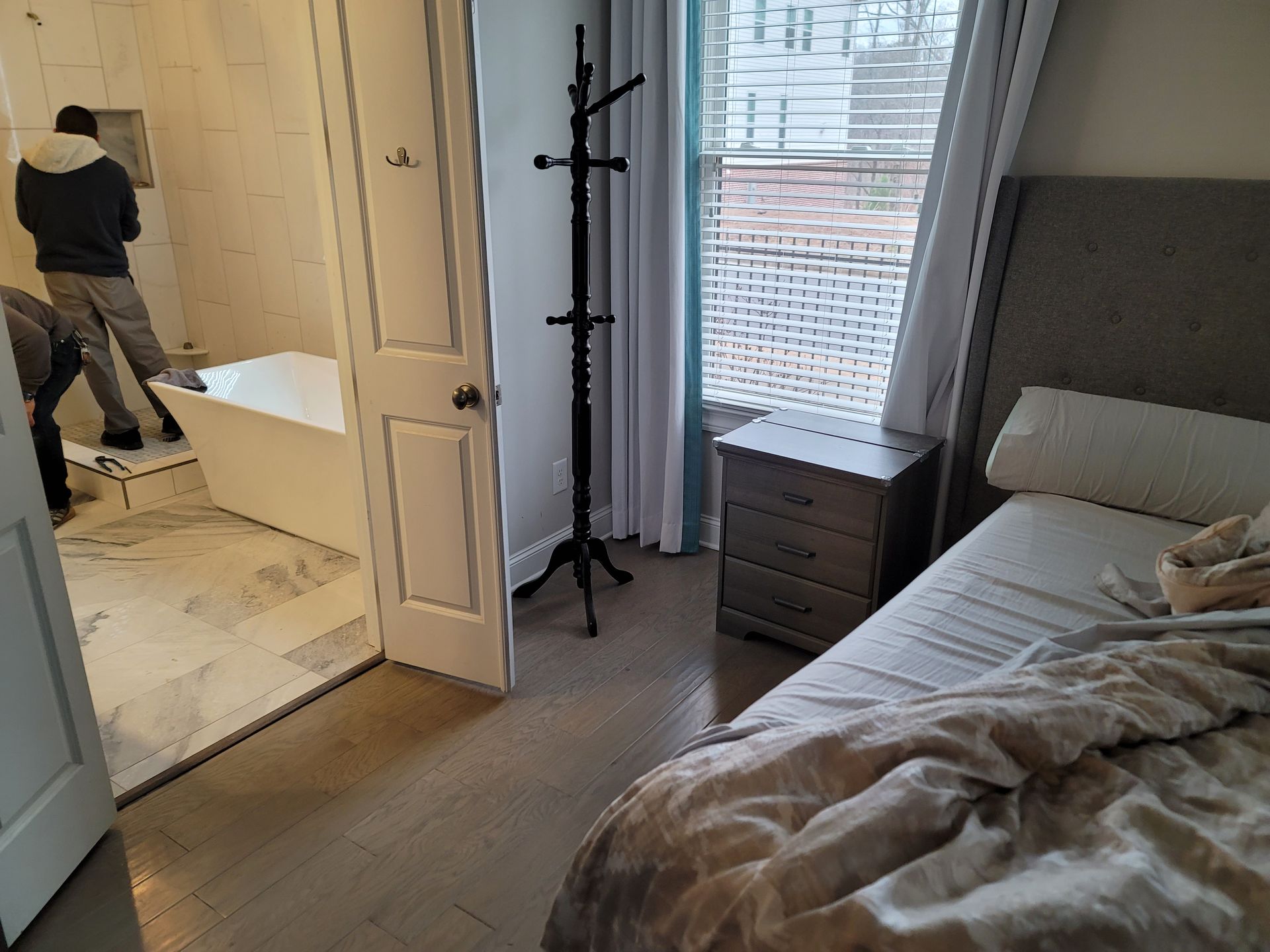 A bedroom with a bed , nightstand , and a coat rack.