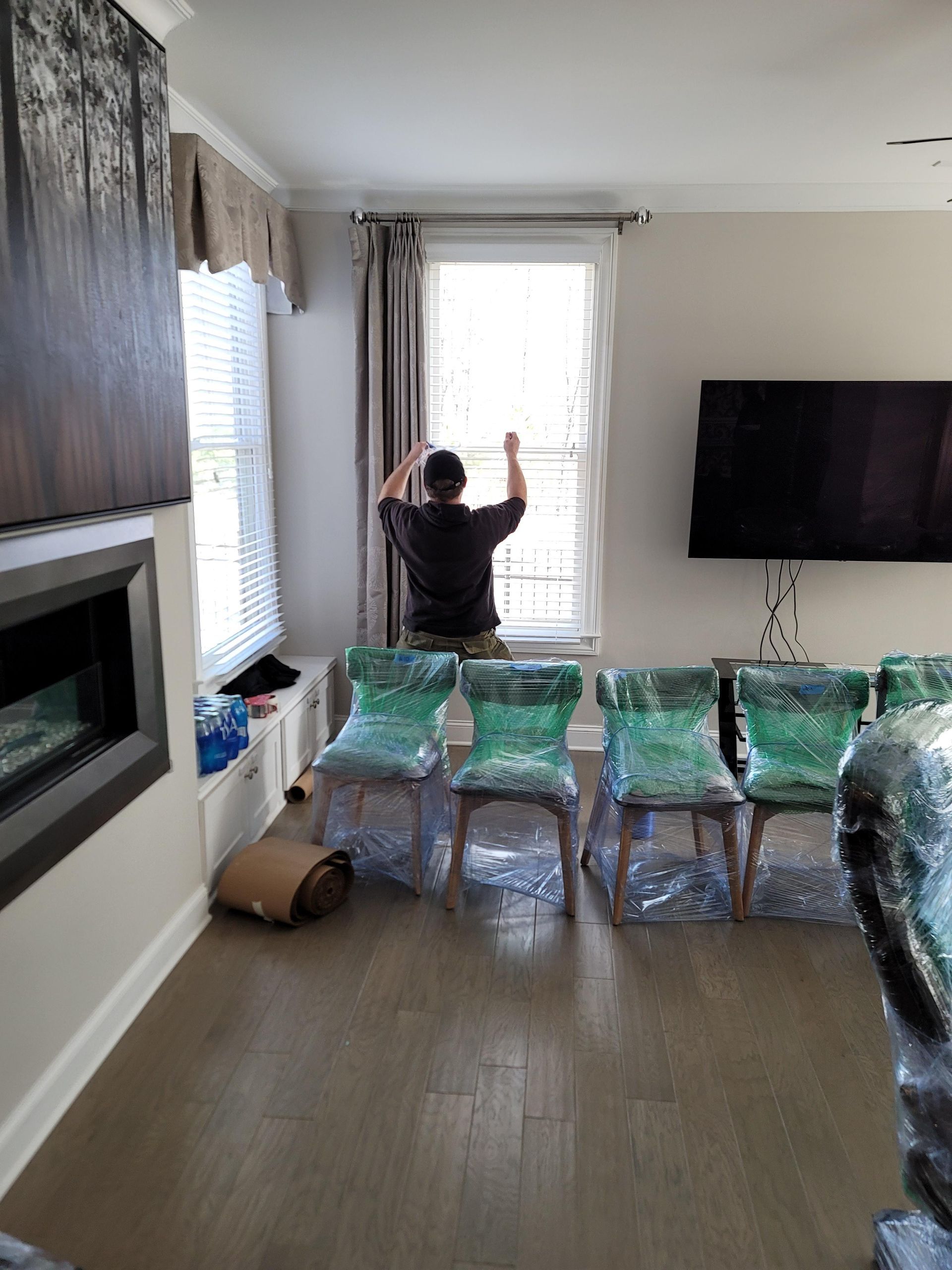 A man is standing in a living room looking out a window.