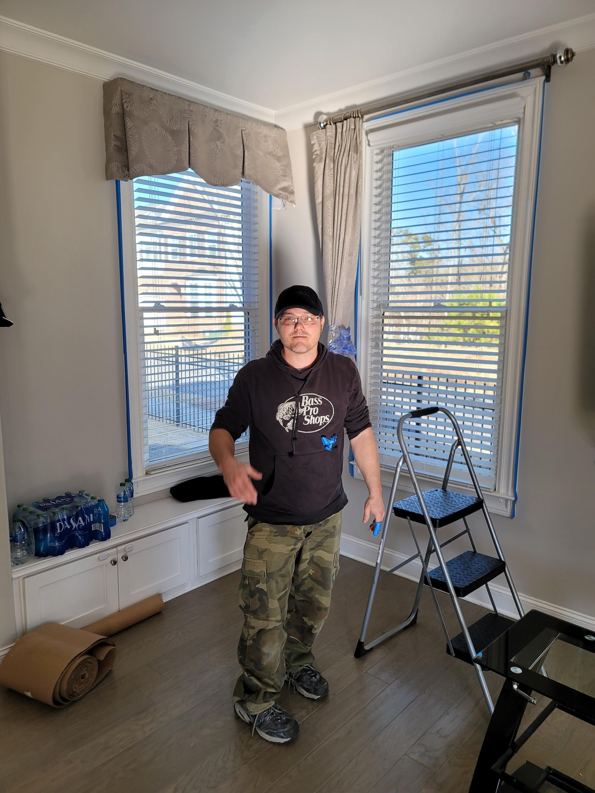 A man is standing in front of a window in a living room.