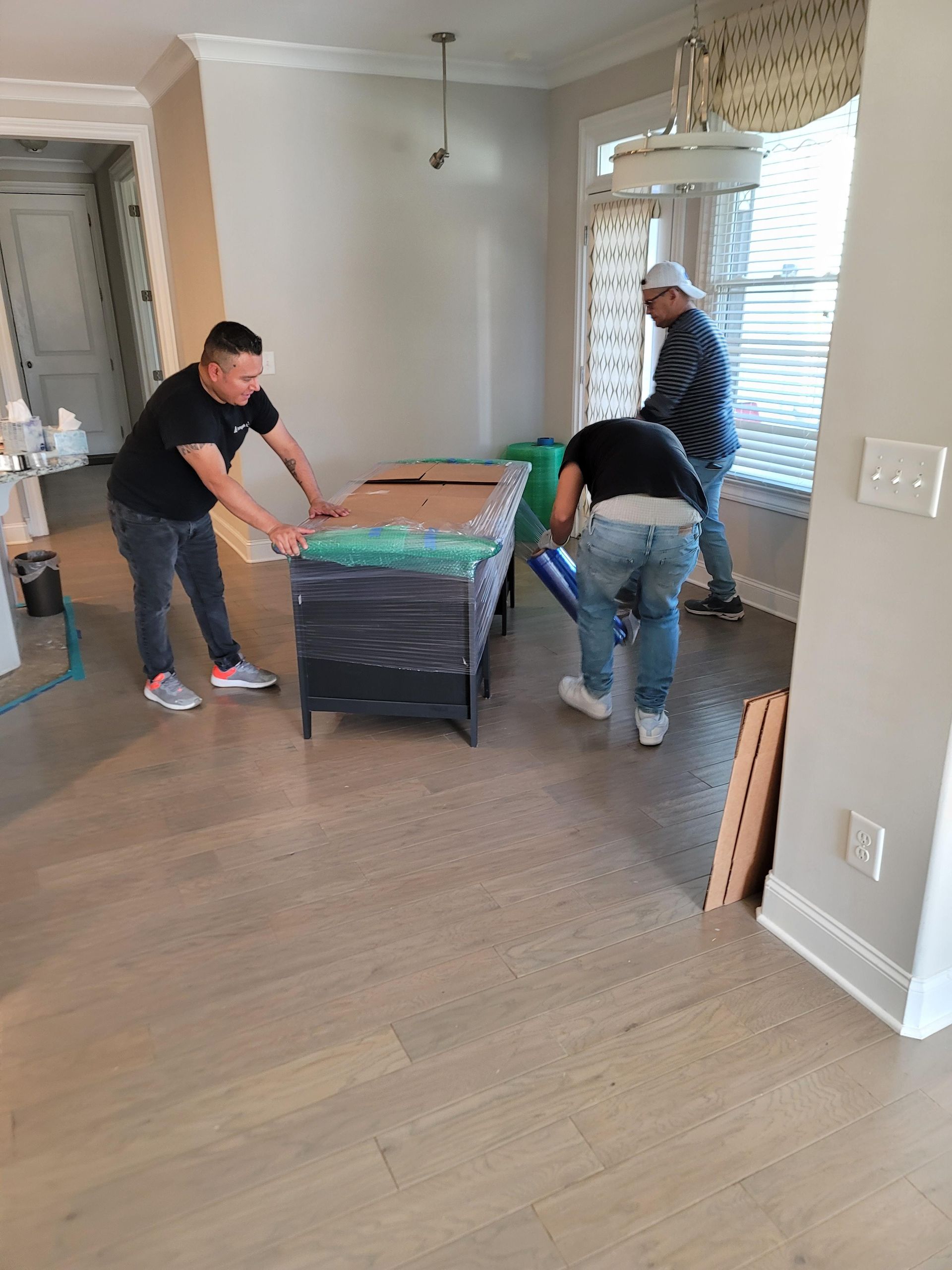 A group of men are moving a table in a living room.