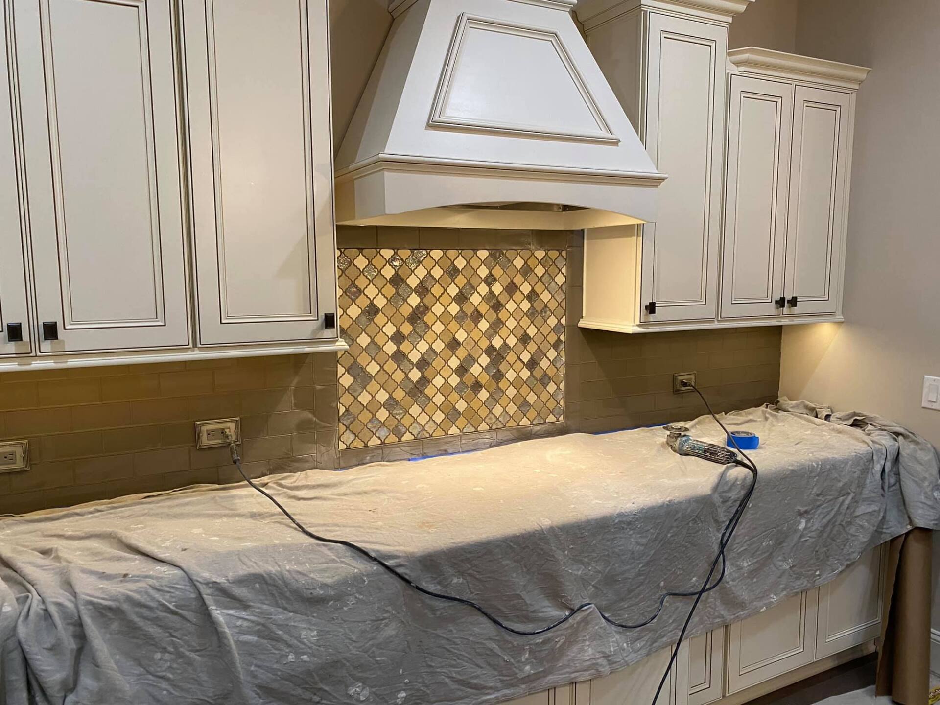 A kitchen with white cabinets and a hood is being remodeled.