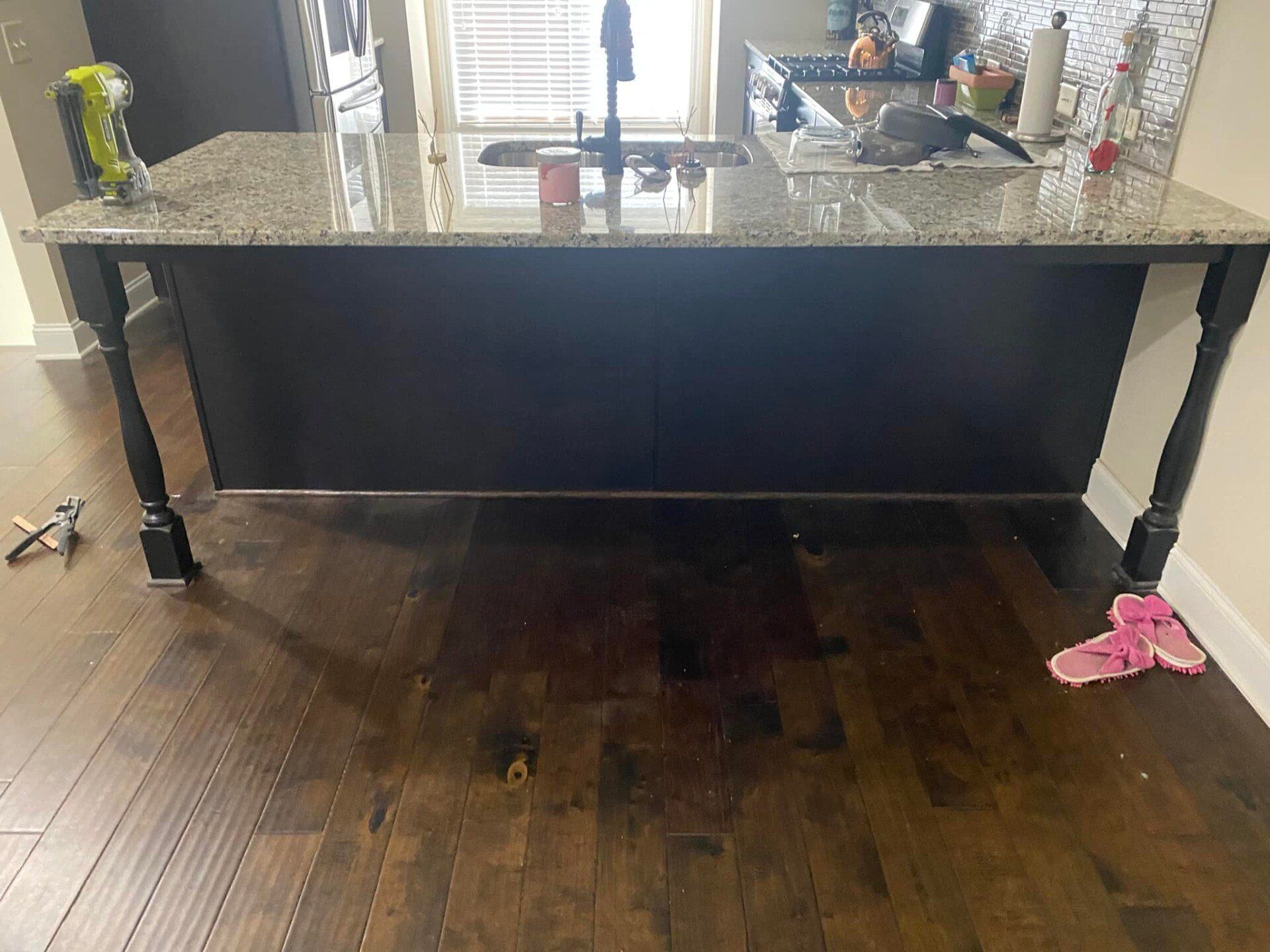 A kitchen with a black island and a granite counter top.