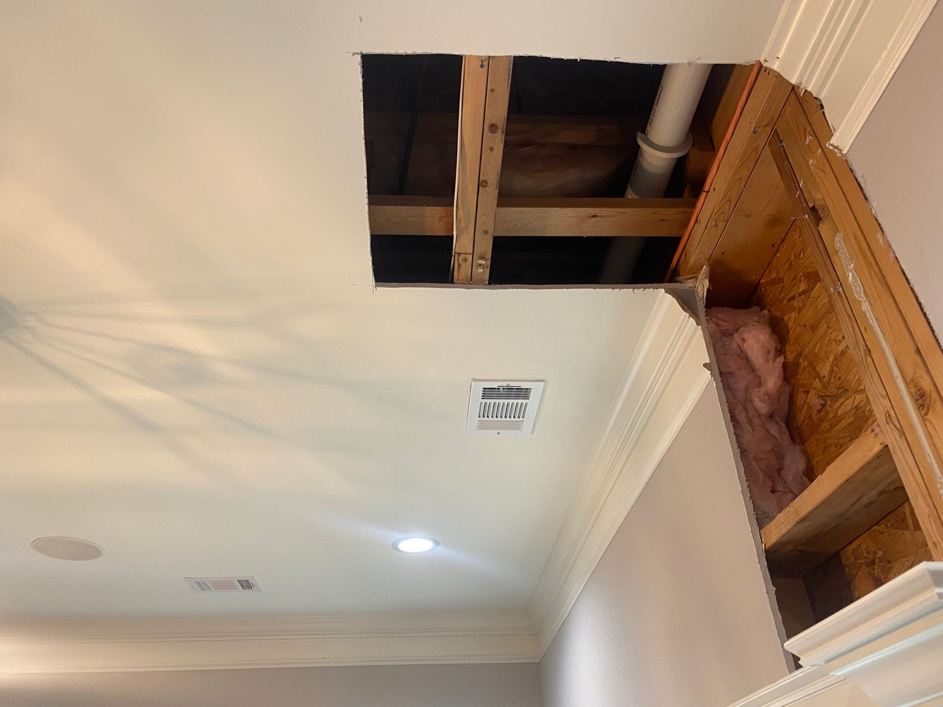 A hole in the ceiling of a room with a pipe coming out of it.