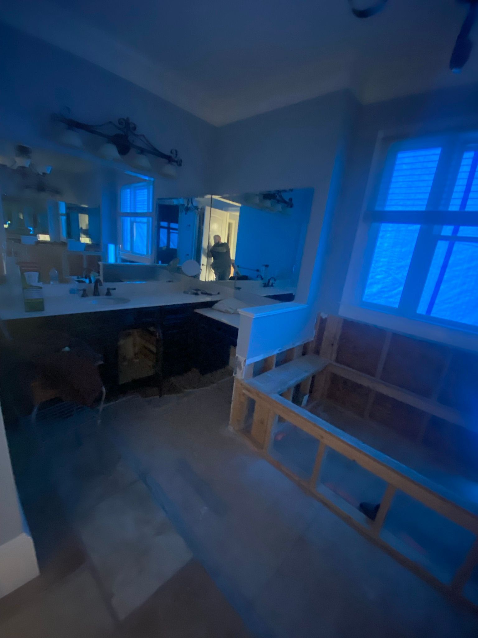 A bathroom under construction with blue lights on the walls and windows.