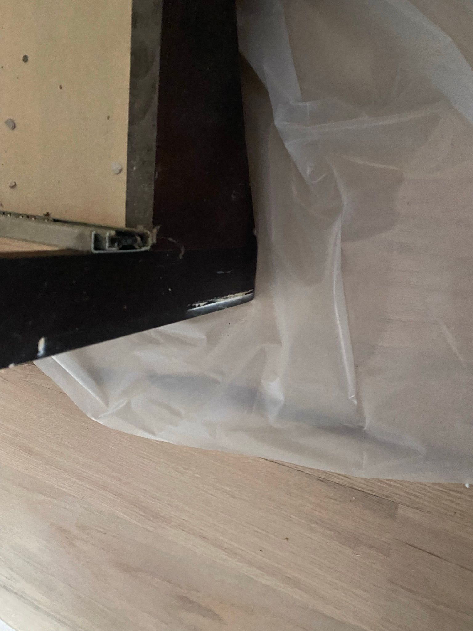 A piece of plastic is laying on the floor next to a piece of wood.