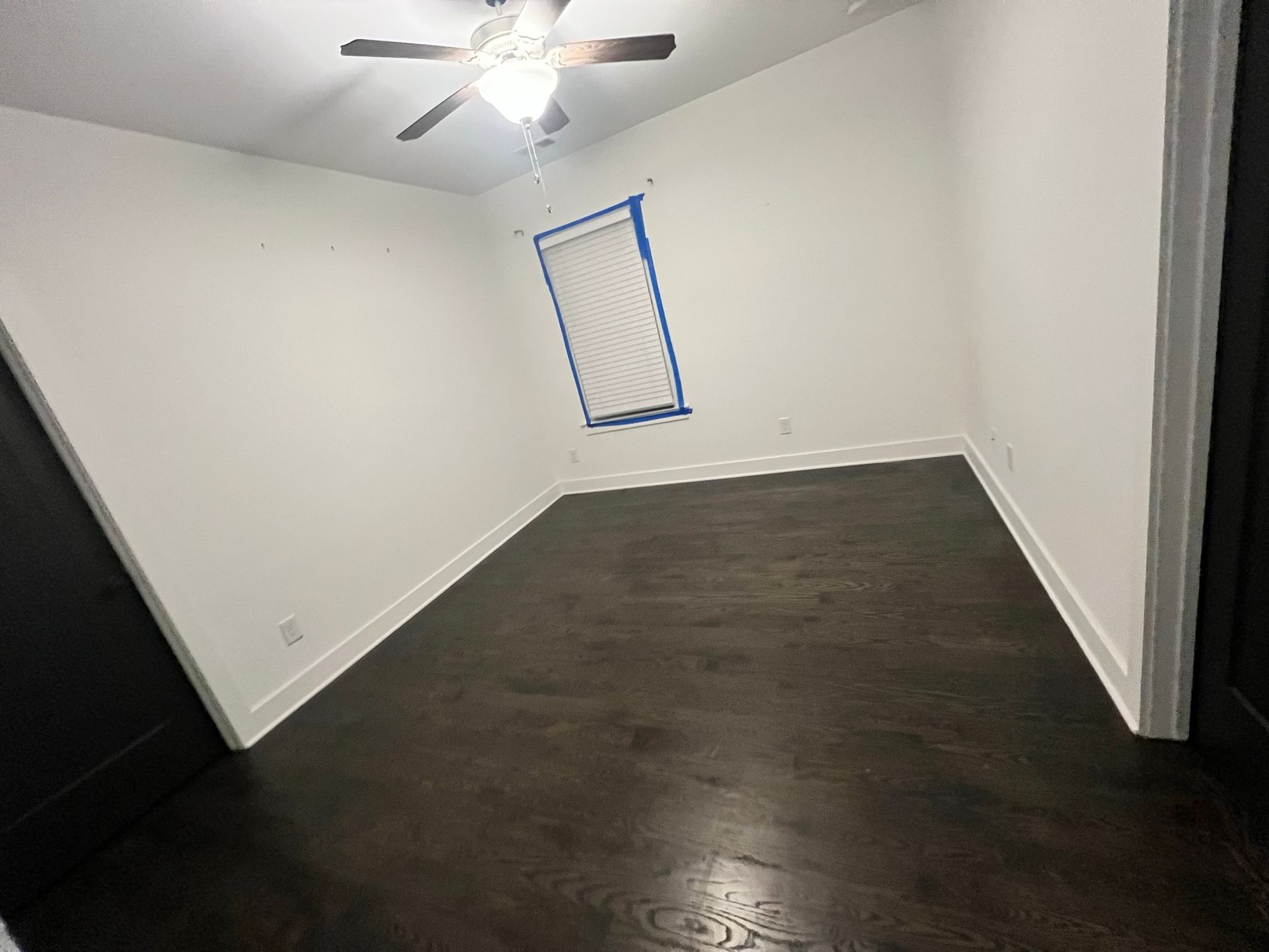 An empty room with a ceiling fan and a window.
